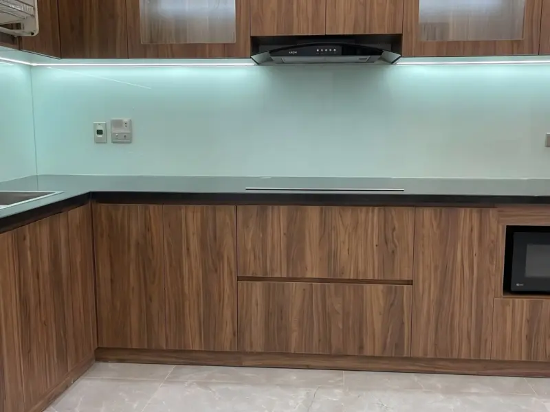 Góc nhìn ngang khu vực tủ dưới và bếp từ của công trình tủ Bếp Cánh Gỗ Nhựa Chống Nước Phủ Melamine Cho Gia Đình Anh Khánh tại Yên Nghĩa, Hà Nội
