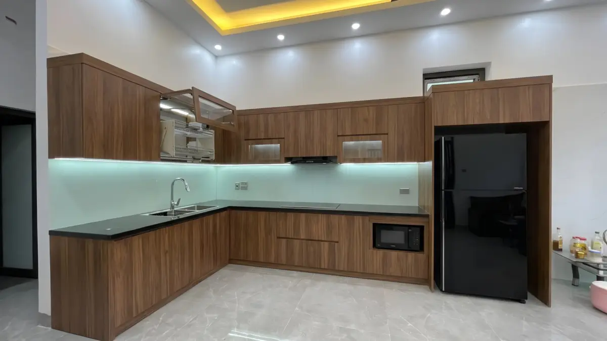 Góc nhìn toàn cảnh bếp chữ L của công trình tủ Bếp Cánh Gỗ Nhựa Chống Nước Phủ Melamine Cho Gia Đình Anh Khánh tại Yên Nghĩa, Hà Nội